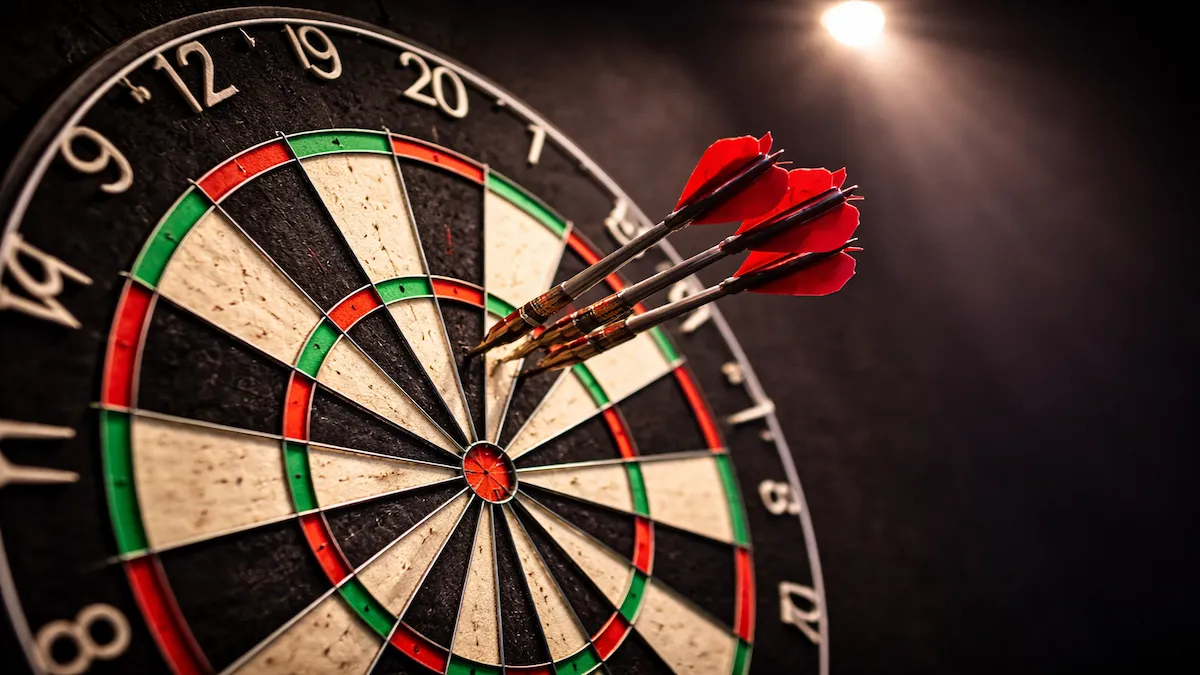 Nahaufnahme eines Dartboards mit Pfeilen im Triple-20-Segment